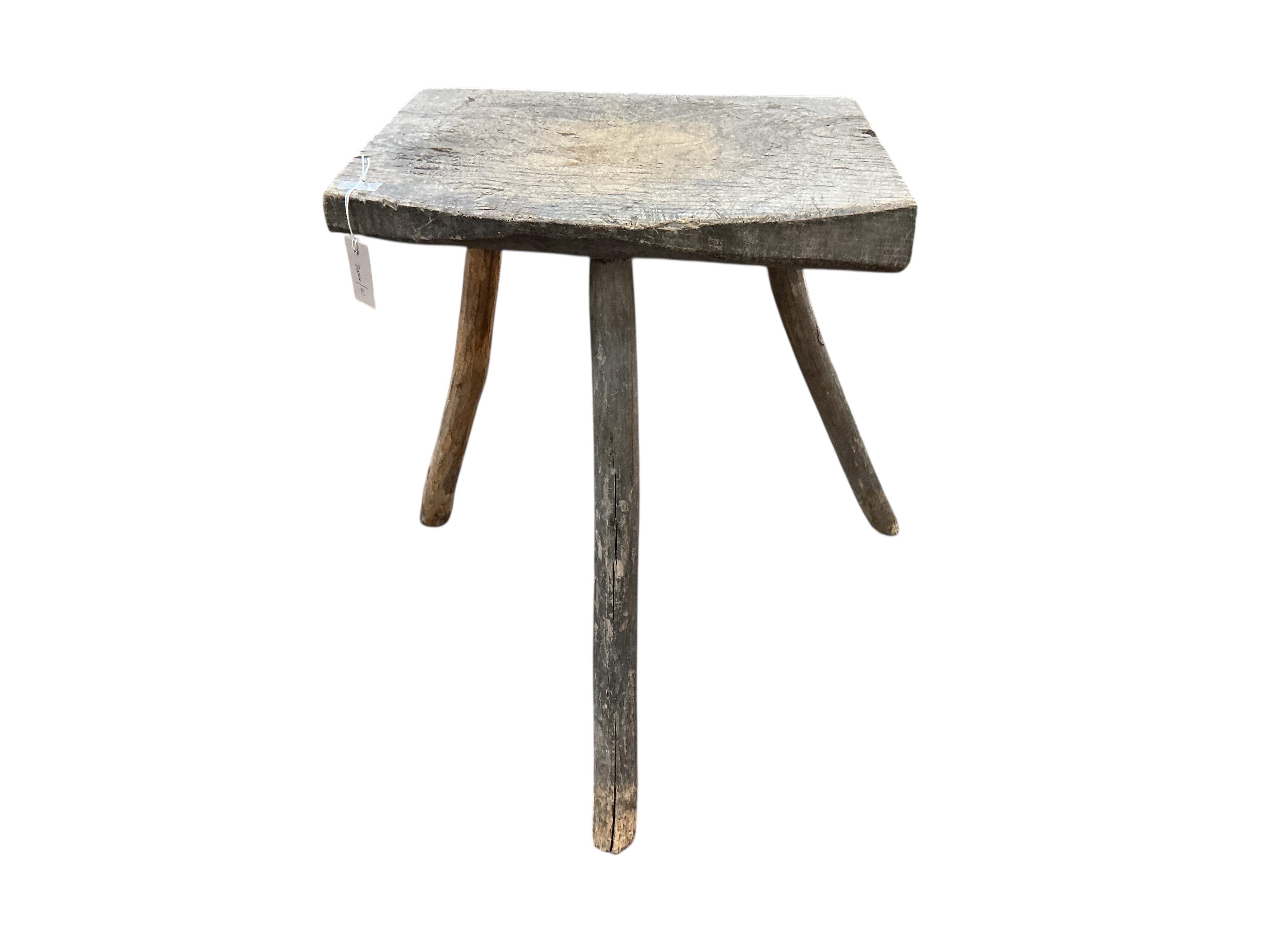 A French Provincial elm three legged block, width 54cm, depth 41cm, height 73cm